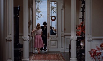 Movie still from “Giant” (1956), directed by George Stevens – A man and a woman are walking through a doorway; Wide shot, High angle