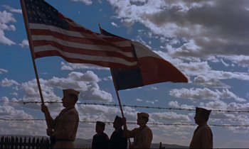 Movie still from “Giant” (1956), directed by George Stevens – A group of men standing next to each other holding flags; Extreme Wide shot, Low angle