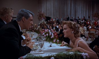 Movie still from “Giant” (1956), directed by George Stevens – A man and a woman sitting at a dinner table; Medium shot, Over the shoulder angle