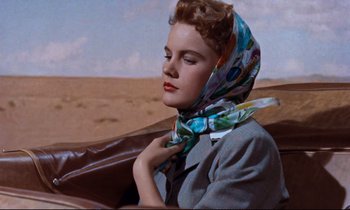 Movie still from “Giant” (1956), directed by George Stevens – A woman with a scarf around her neck is sitting in a car; Close Up shot, Low angle