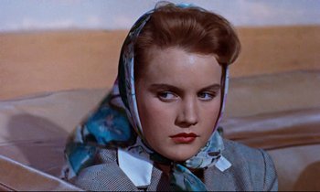 Movie still from “Giant” (1956), directed by George Stevens – A woman wearing a blue scarf and a black and white checkered jacket; Close Up shot, Over the shoulder angle