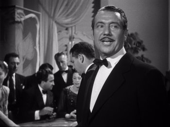 Movie still from “Gilda” (1946), directed by Charles Vidor – A black and white photo of a man in a tuxedo; Medium shot, Low angle