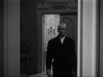 Movie still from “Gilda” (1946), directed by Charles Vidor – A black and white photo of a man standing in a doorway; Medium shot, Low angle