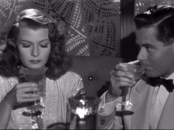 Movie still from “Gilda” (1946), directed by Charles Vidor – A man and a woman drinking wine at a table; Medium shot, High angle