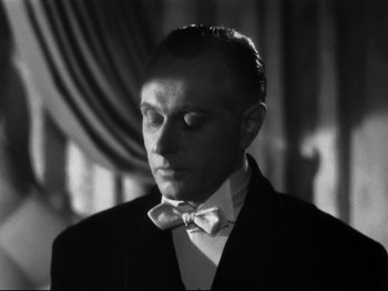 Movie still from “Gilda” (1946), directed by Charles Vidor – A black and white photo of a man wearing a suit and bow tie; Close Up shot, Low angle