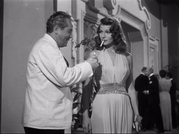 Movie still from “Gilda” (1946), directed by Charles Vidor – An old photo of a man and a woman smoking a cigarette; Medium shot, Low angle