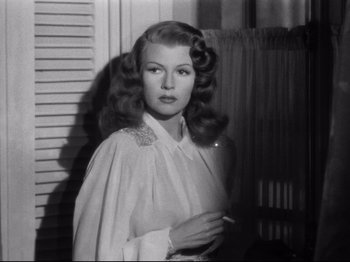 Movie still from “Gilda” (1946), directed by Charles Vidor – A black - and - white photo of a woman in a white dress; Close Up shot, Over the shoulder angle