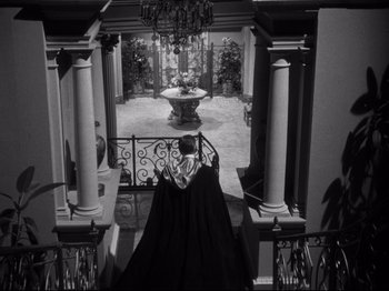 Movie still from “Gilda” (1946), directed by Charles Vidor – A woman in a black dress standing on a staircase; Extreme Wide shot, High angle