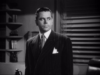Movie still from “Gilda” (1946), directed by Charles Vidor – A man wearing a suit and tie standing in a room; Close Up shot, Low angle