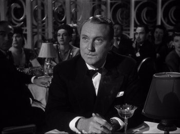 Movie still from “Gilda” (1946), directed by Charles Vidor – A man sitting at a table with a martini glass in front of him; Close Up shot, Low angle
