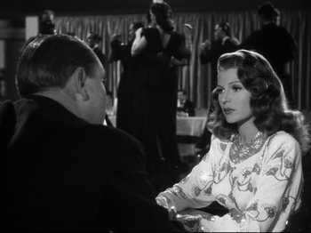 Movie still from “Gilda” (1946), directed by Charles Vidor – A man and a woman sitting at a dinner table; Medium shot, Over the shoulder angle