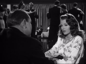 Movie still from “Gilda” (1946), directed by Charles Vidor – An old photo of a woman talking to an older man; Medium shot, Over the shoulder angle
