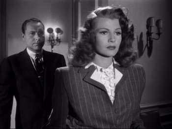 Movie still from “Gilda” (1946), directed by Charles Vidor – A man and a woman standing next to each other in a room; Medium shot, Over the shoulder angle