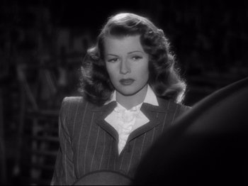 Movie still from “Gilda” (1946), directed by Charles Vidor – A black and white photo of a woman in a suit; Close Up shot, Over the shoulder angle