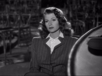 Movie still from “Gilda” (1946), directed by Charles Vidor – A black and white photo of a woman in a suit; Medium shot, Over the shoulder angle