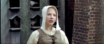 Movie still from “Girl with a Pearl Earring” (2003), directed by Peter Webber – A young woman in medieval clothing with a white hat; Close Up shot, Low angle