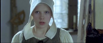 Movie still from “Girl with a Pearl Earring” (2003), directed by Peter Webber – A young girl wearing a white hat and a dress; Close Up shot, Low angle