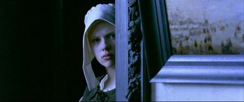 Movie still from “Girl with a Pearl Earring” (2003), directed by Peter Webber – A young woman wearing a white hat looking out a window; Close Up shot, Low angle