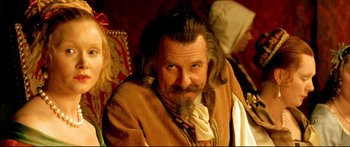 Movie still from “Girl with a Pearl Earring” (2003), directed by Peter Webber – A man with long hair and a beard sitting on a chair; Close Up shot, Over the shoulder angle