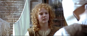 Movie still from “Girl with a Pearl Earring” (2003), directed by Peter Webber – A young girl with blonde hair is looking at the camera; Close Up shot, Over the shoulder angle