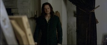 Movie still from “Girl with a Pearl Earring” (2003), directed by Peter Webber – A man with long black hair standing in a room; Medium shot, Over the shoulder angle