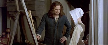 Movie still from “Girl with a Pearl Earring” (2003), directed by Peter Webber – A man standing next to another man in a room; Medium shot, Over the shoulder angle