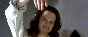 Movie still from “Girl with a Pearl Earring” (2003), directed by Peter Webber – A man with long black hair is combing another man's hair; Close Up shot, Low angle