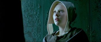 Movie still from “Girl with a Pearl Earring” (2003), directed by Peter Webber – A woman wearing a hood looking to her left; Close Up shot, Low angle