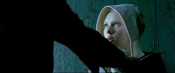 Movie still from “Girl with a Pearl Earring” (2003), directed by Peter Webber – A young girl wearing a hood looking up at the camera; Close Up shot, Low angle