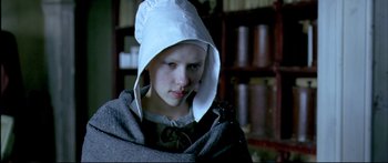 Movie still from “Girl with a Pearl Earring” (2003), directed by Peter Webber – A young girl wearing a white hat and a cloak; Close Up shot, Low angle