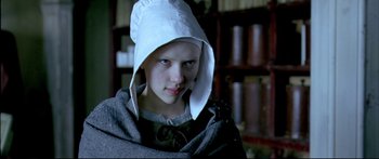 Movie still from “Girl with a Pearl Earring” (2003), directed by Peter Webber – A young girl wearing a white hat and a cape; Close Up shot, Low angle
