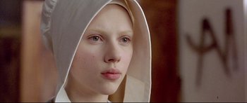 Movie still from “Girl with a Pearl Earring” (2003), directed by Peter Webber – A young woman wearing a white hat and a white dress; Close Up shot, High angle