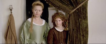 Movie still from “Girl with a Pearl Earring” (2003), directed by Peter Webber – Two young women in medieval garb standing next to each other in front of a drape; Medium shot, High angle
