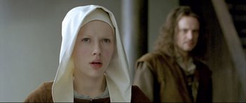 Movie still from “Girl with a Pearl Earring” (2003), directed by Peter Webber – A young woman wearing a white headscarf and looking at the camera; Close Up shot, Over the shoulder angle