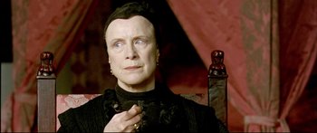 Movie still from “Girl with a Pearl Earring” (2003), directed by Peter Webber – An older woman is holding a cigarette in her mouth; Close Up shot, Low angle