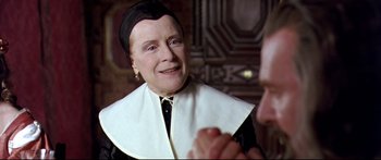 Movie still from “Girl with a Pearl Earring” (2003), directed by Peter Webber – An older woman wearing a nun's hat and a neck scarf; Close Up shot, Over the shoulder angle