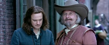Movie still from “Girl with a Pearl Earring” (2003), directed by Peter Webber – A man in a cowboy hat standing next to another man; Close Up shot, Over the shoulder angle