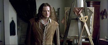 Movie still from “Girl with a Pearl Earring” (2003), directed by Peter Webber – A man standing in front of a ladder in a room; Medium shot, Over the shoulder angle
