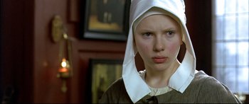 Movie still from “Girl with a Pearl Earring” (2003), directed by Peter Webber – A young girl wearing a nun's hat in front of a painting; Close Up shot, High angle