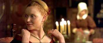 Movie still from “Girl with a Pearl Earring” (2003), directed by Peter Webber – A woman in a red dress with a candle in the background; Close Up shot, Over the shoulder angle