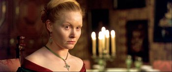 Movie still from “Girl with a Pearl Earring” (2003), directed by Peter Webber – A woman in a red dress with a candle in the background; Close Up shot, Over the shoulder angle