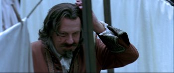Movie still from “Girl with a Pearl Earring” (2003), directed by Peter Webber – A man with long hair and a goatee is combing his hair; Close Up shot, Low angle