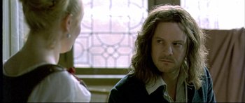 Movie still from “Girl with a Pearl Earring” (2003), directed by Peter Webber – A man with long hair is looking at the camera; Close Up shot, Over the shoulder angle