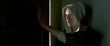 Movie still from “Girl with a Pearl Earring” (2003), directed by Peter Webber – A young woman wearing a white hat and a black dress; Close Up shot, Low angle
