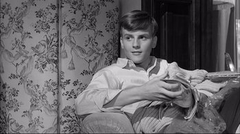 Movie still from “Girl with a Suitcase” (1961), directed by Valerio Zurlini – A young man sitting on a couch holding a blanket; Close Up shot, High angle