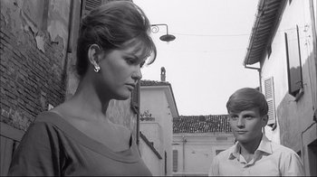 Movie still from “Girl with a Suitcase” (1961), directed by Valerio Zurlini – A woman standing next to a man in a courtyard; Medium shot, Low angle