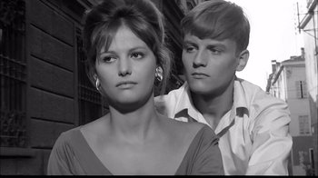 Movie still from “Girl with a Suitcase” (1961), directed by Valerio Zurlini – A man and a woman standing next to each other in front of a building; Close Up shot, High angle