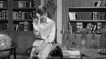 Movie still from “Girl with a Suitcase” (1961), directed by Valerio Zurlini – A man sitting on a chair next to a book shelf; Medium shot, High angle