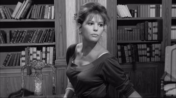 Movie still from “Girl with a Suitcase” (1961), directed by Valerio Zurlini – A black and white photo of a woman in front of bookcases; Medium shot, Low angle
