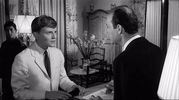 Movie still from “Girl with a Suitcase” (1961), directed by Valerio Zurlini – Two men in suits are talking to each other in a living room; Medium shot, Over the shoulder angle